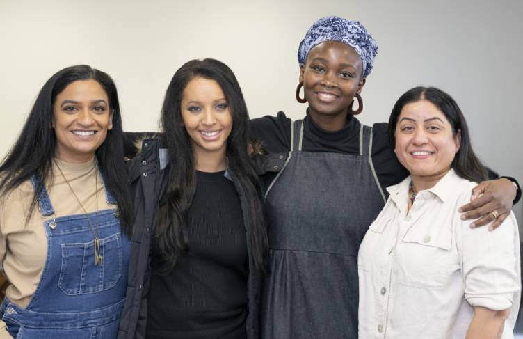 Four women from different cultural backgrounds standing shoulder to shoulder