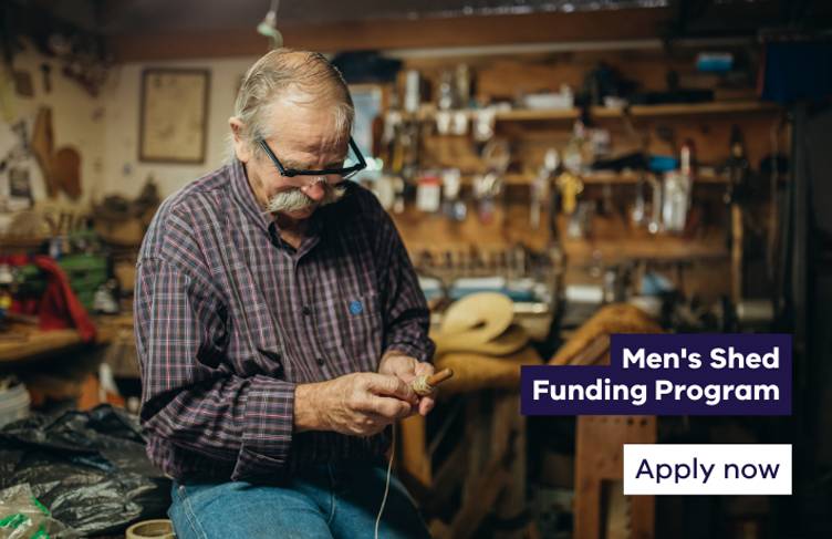 Older man sitting on a bench in a tool shed winding twine on to a spool