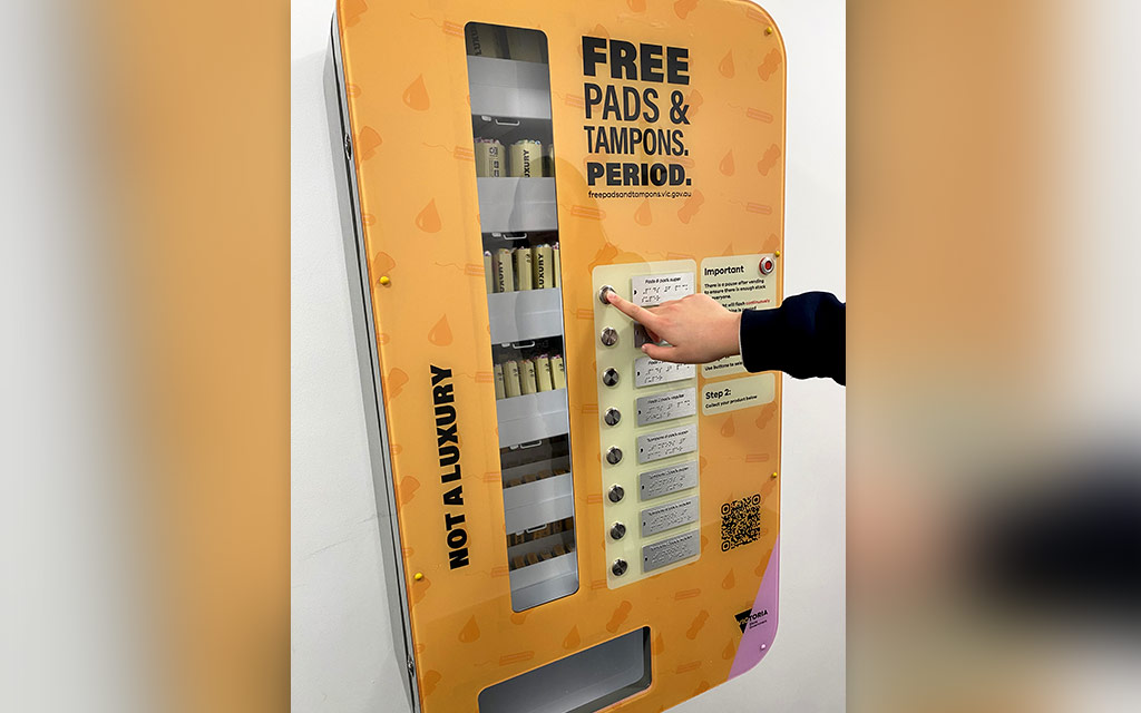 A person selecting a product from a pads and tampons vending machine