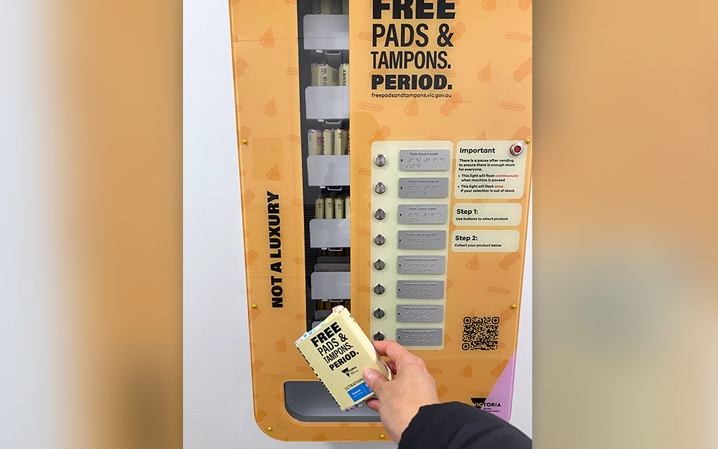 A person holding a product dispensed by a pads and tampons vending machine