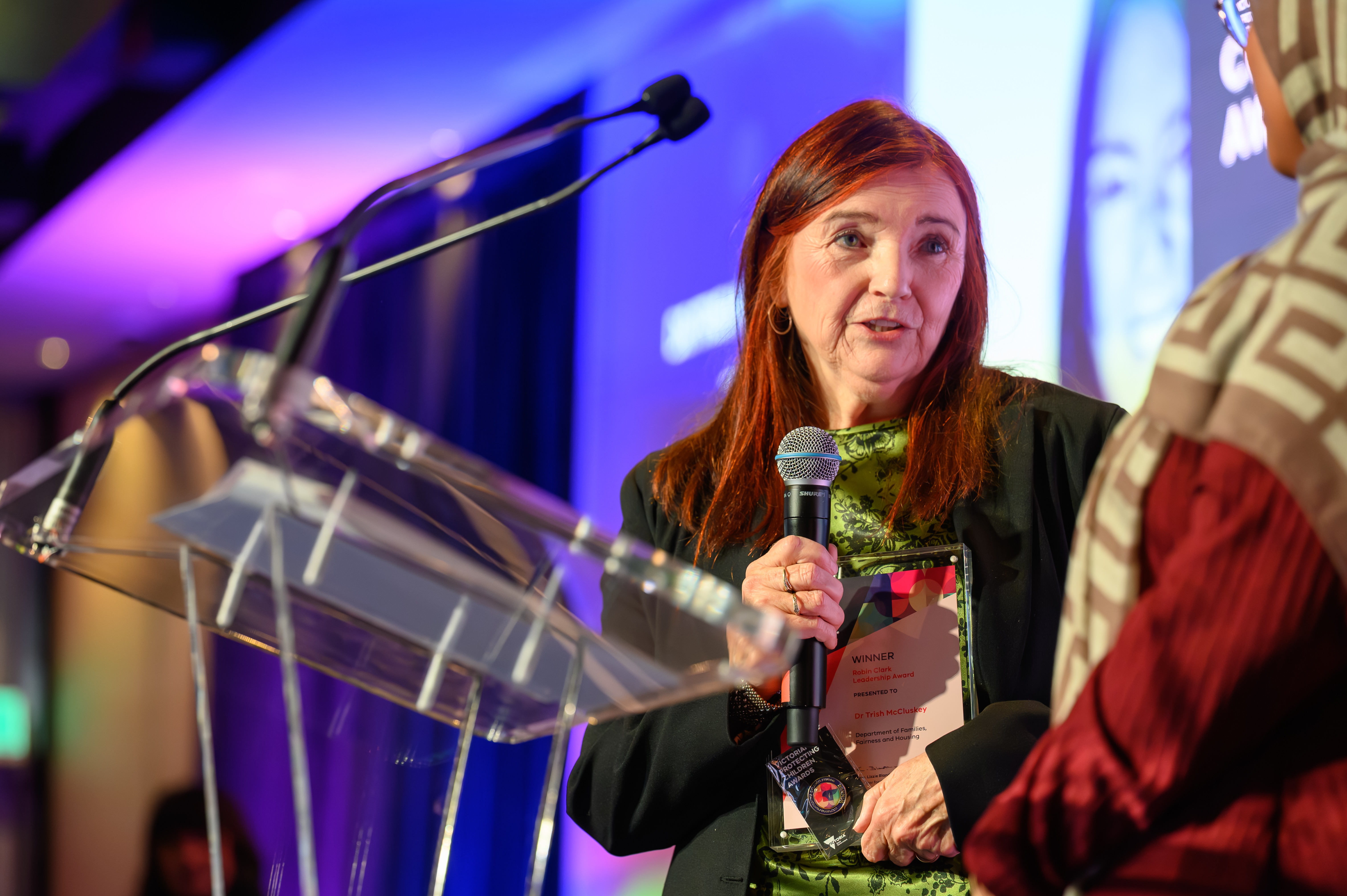 A woman speaking into a microphone at the awards ceremony