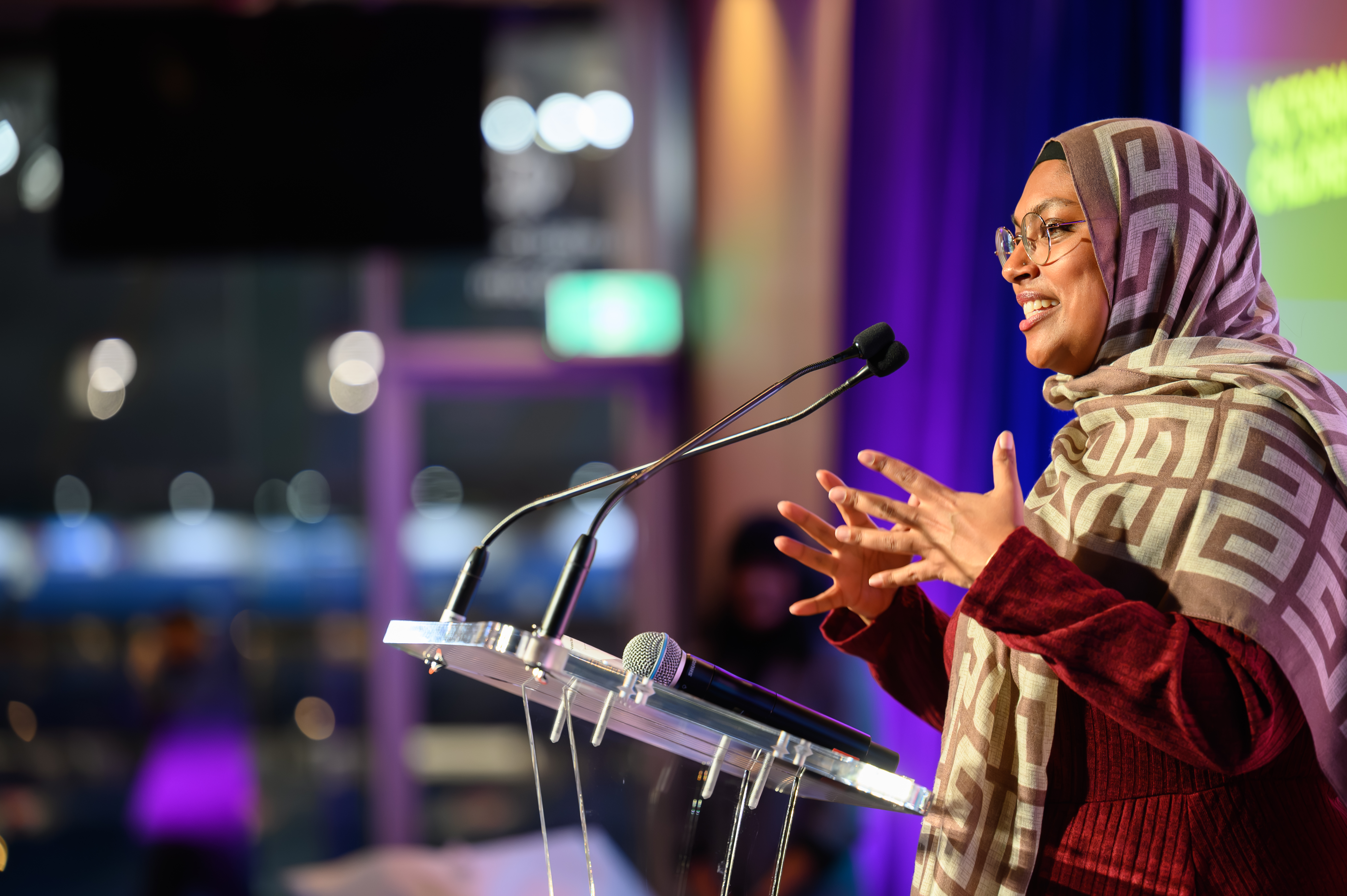 A woman speaking into a microphone at a podium at an awards ceremony