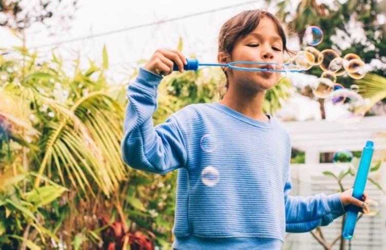 Child in garden blowing bubbles